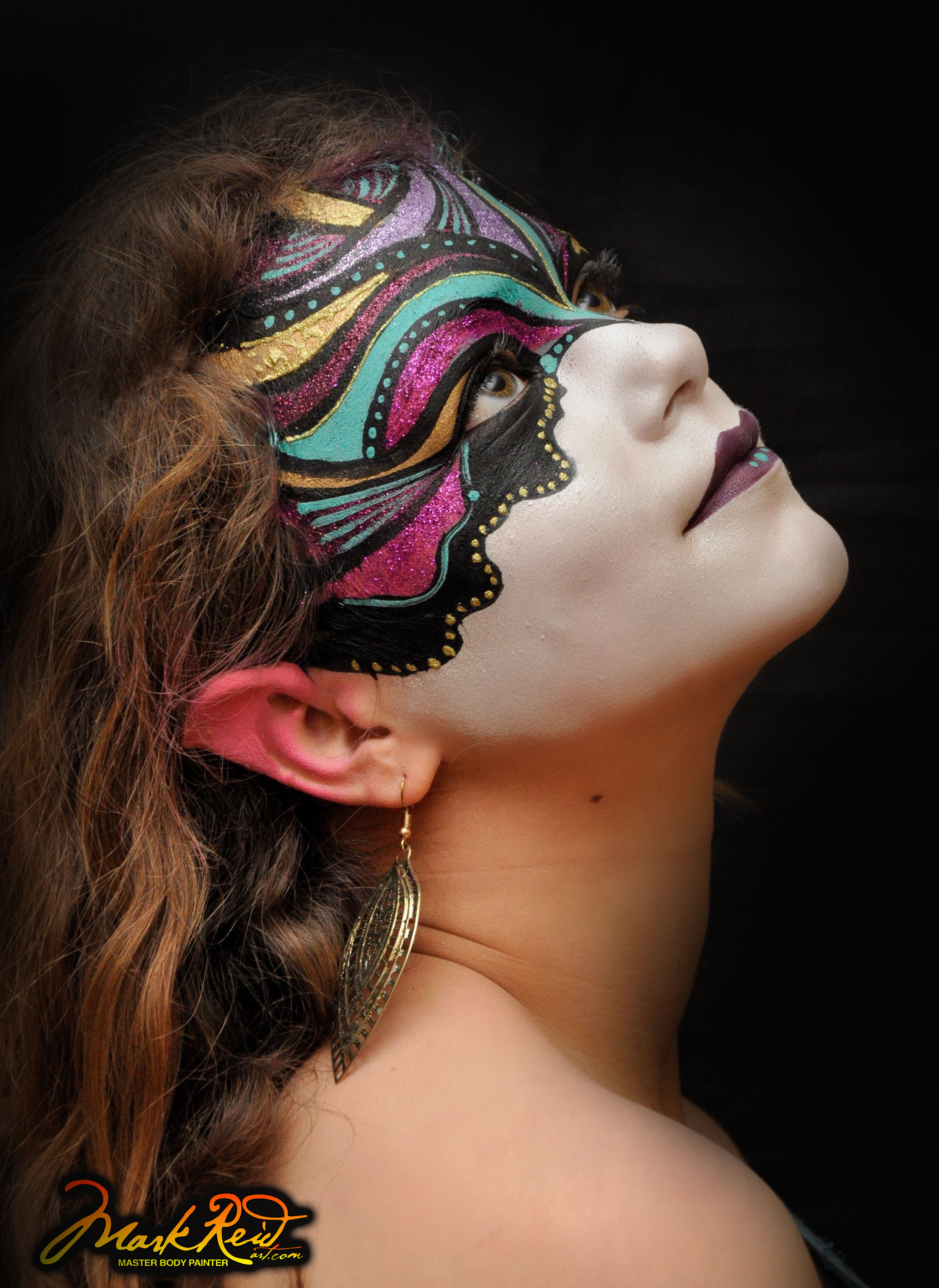 face painting of an intricate mask on a brunette woman looking up and to the right